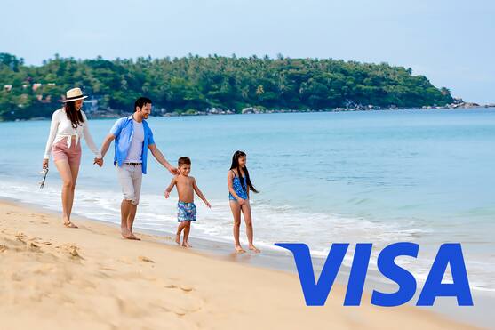 Family of four walking on beach and a Visa logo in bottom right hand corner of image