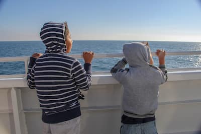 Young children looking to the sea whale watching from a boat