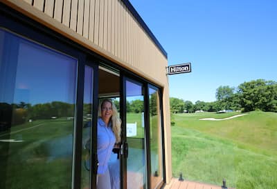 Women looking out of pop-up Hilton on golf course