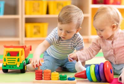 A small boy and girl playing with toys in a playroom setting.
