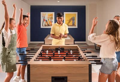 A mixed group of excited older kids playing table football.