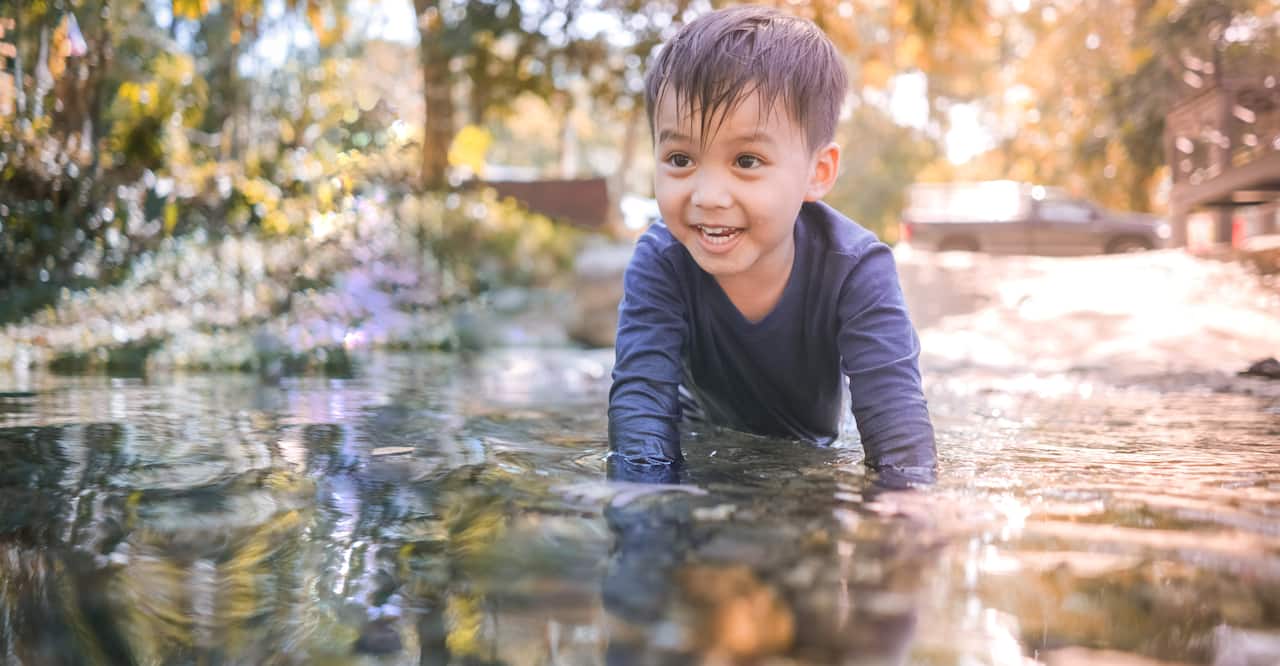 Happy child playing in water pond
