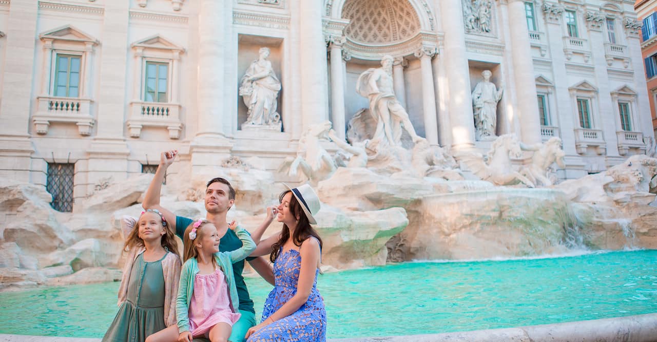 Happy family trowing coins at Trevi Fountain, Rome, for good luck. 