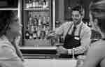Barman pouring a cocktail into a glass.