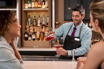 Barman pouring a cocktail into a glass.