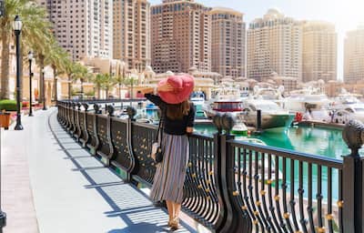 Woman looks at the Marina Walkway in Porto Arabia at the Pearl in Doha, Qatar.
