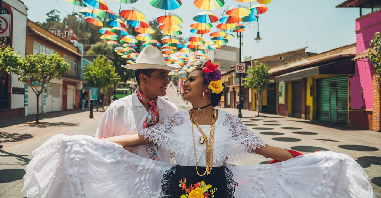 Mexican dancers doing their performance in the street adorned with colored umbrellas.