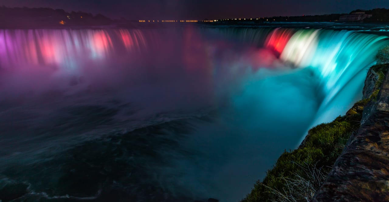 Niagara Falls illumination with colorful lights at night.