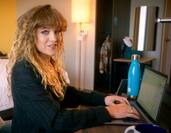 Woman sits at desk in hotel room