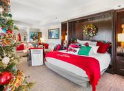 Christmas themed hotel room with tree and red and green bed