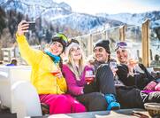 Group of friends talking and having fun in a outdoor restaurant on winter holidays at a ski lodge.
