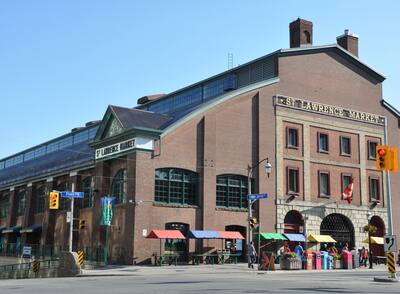 St. Lawrence Market - a large, industrial building that houses a public market in Toronto that has vendor tables with colorful tops outside.