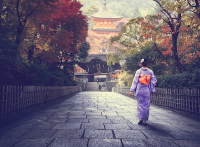 Japanese woman walking to red pagoda, Japan.