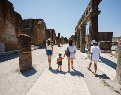 Back of family tourist walking at Pompeii ancient city, Italy.