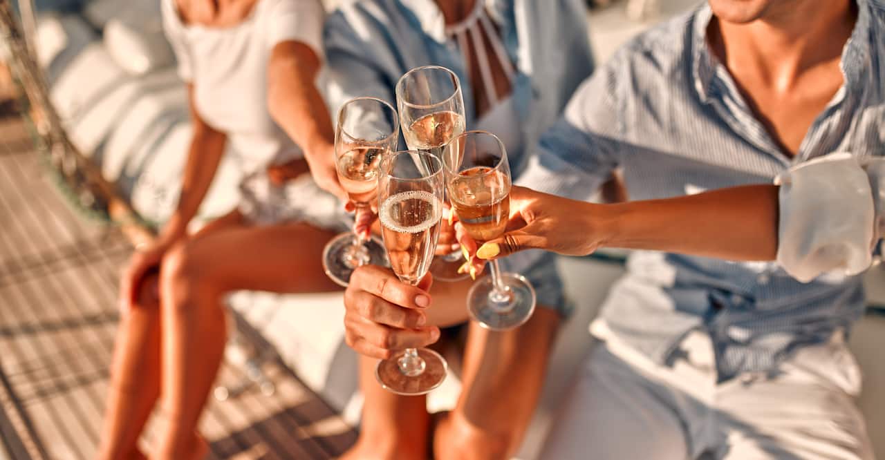 Image of group of friends relaxing on luxury yacht and drinking champagne.
