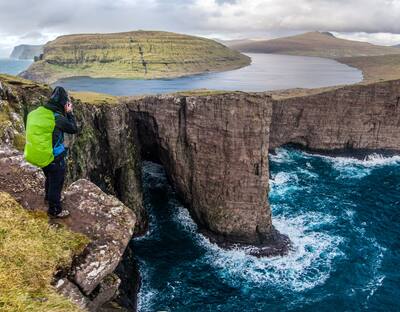 Panoramatic view into the bay with women hiker photographer, Faroes Islands
