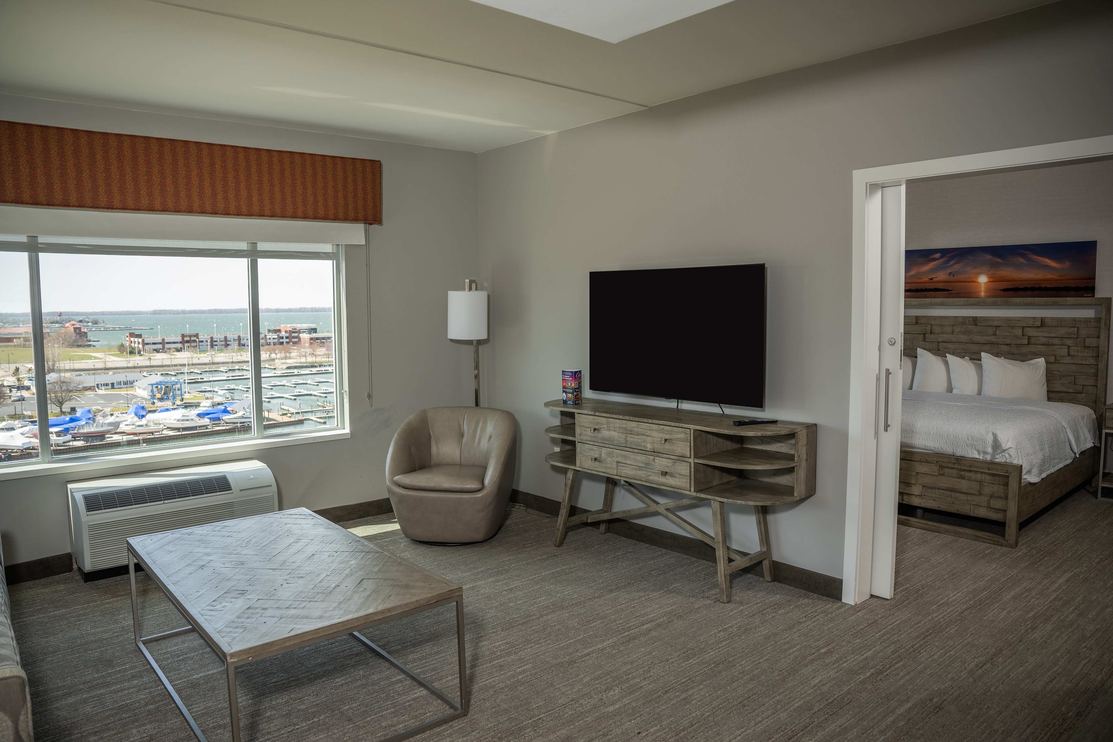 Living Area with HDTV, Table, Soft chair and a Large Bed in a Suite 