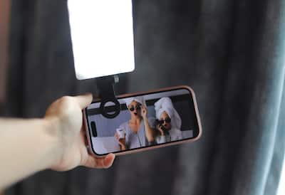 Outstretched hand holds cell phone with light attached