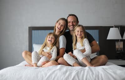 Smiling family sits on bed together