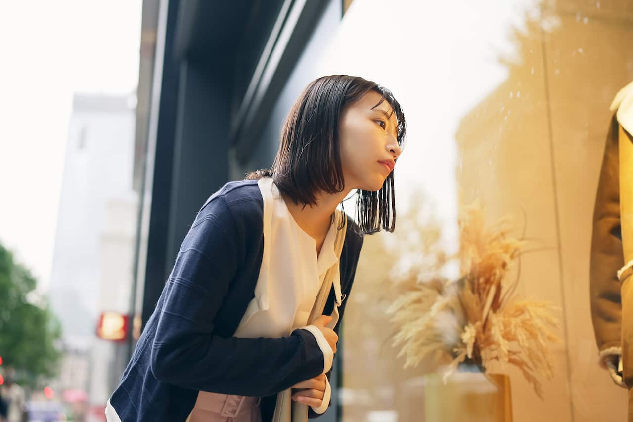 Alışveriş yaparken mağaza vitrinindeki monta bakan genç kadın