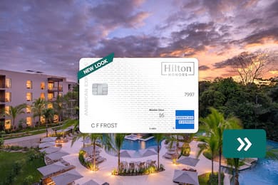 The Hilton Honors American Express Card with a resort hotel in the background