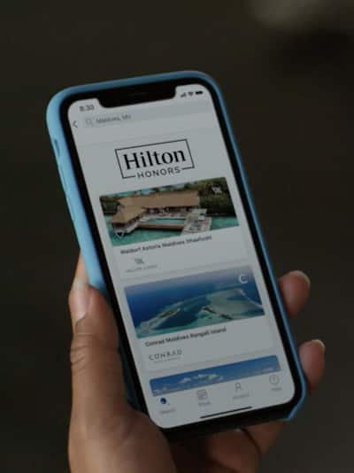 Woman's hand holding iPhone open on the Hilton Honors app
