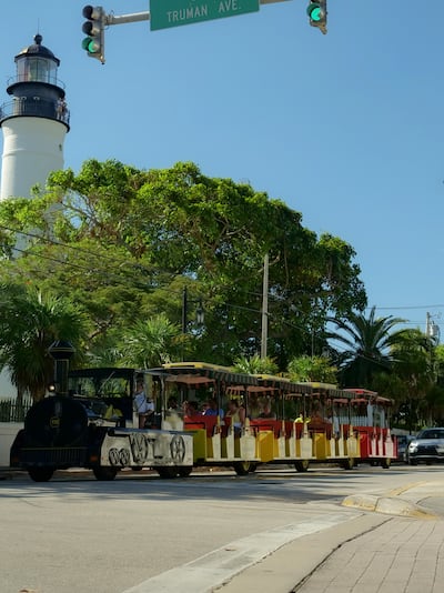 lighthouse in keywest with greenery and a streetcar in the background
