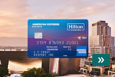 The Hilton Honors American Express Business Card with a city skyline in the background