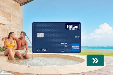 The Hilton Honors American Express Surpass® Card with a couple sitting beside a jacuzzi in the background