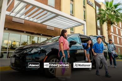 Family exiting their car rental at a Home2 Suites hotel
