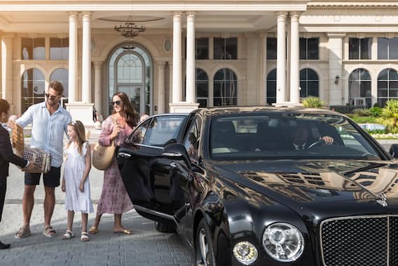 Group of people standing outside property, with woman opening car door