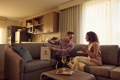 Man and woman sitting on sofa having a takeaway and wine