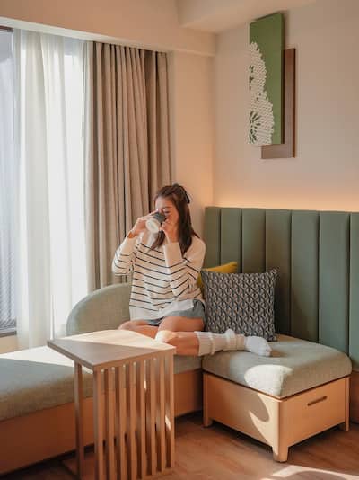 Woman drinking coffee in hotel room