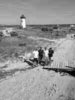 四人站在沙灘上，在架空無人機與狗和海浪同坐