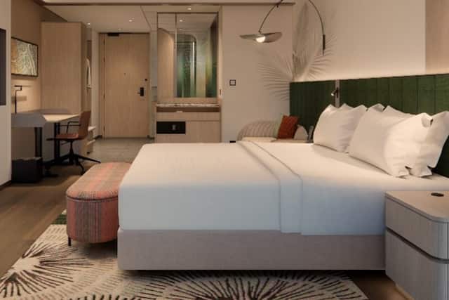 Bed in room with work desk, mirror and chair