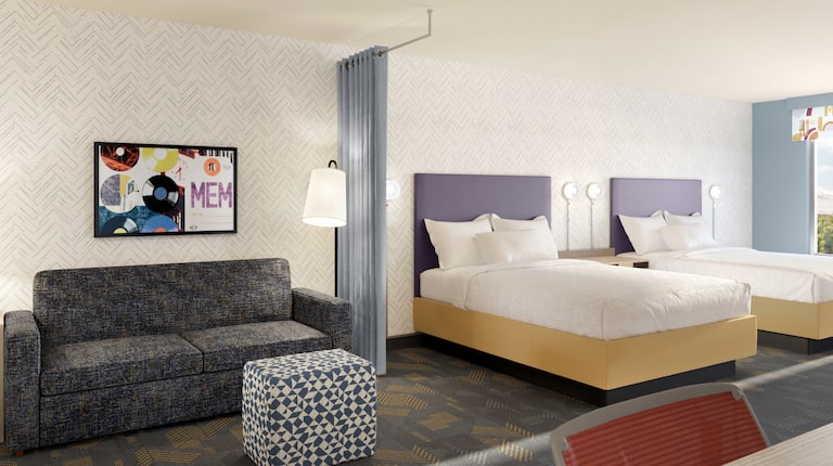 Two beds in room with couch and art on wall