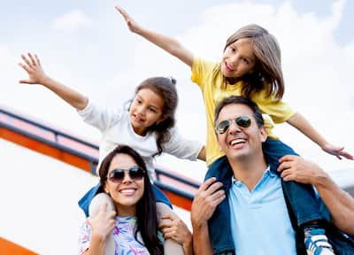 Mother and Father Carrying Young Daughters on Shoulders Outside Airport