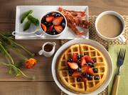 Waffle Topped with Strawberries and Blueberries and a side of Bacon, Fruit and Coffee