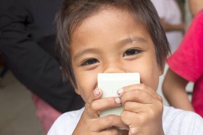 Young boy holding a new bar of soap in front of his smiling face.