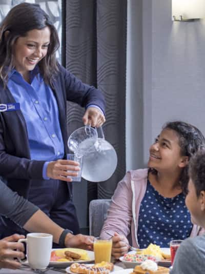 hampton inn employee with family enjoying breakfast