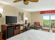 Spacious guestroom featuring comfortable bed, TV, work desk, sofa, and private balcony.