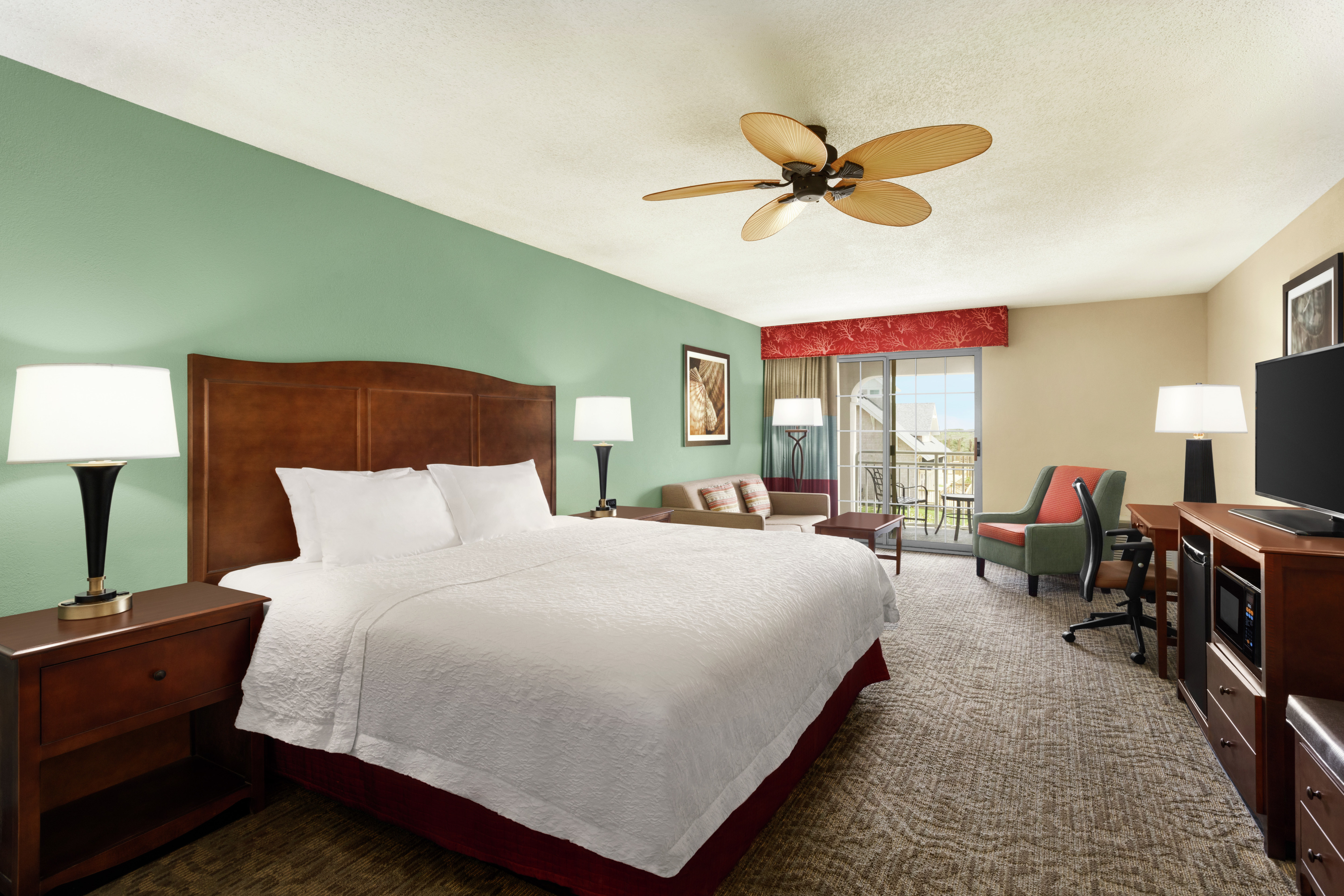 Spacious accessible guestroom featuring comfortable king bed, sofa, and partial ocean view.