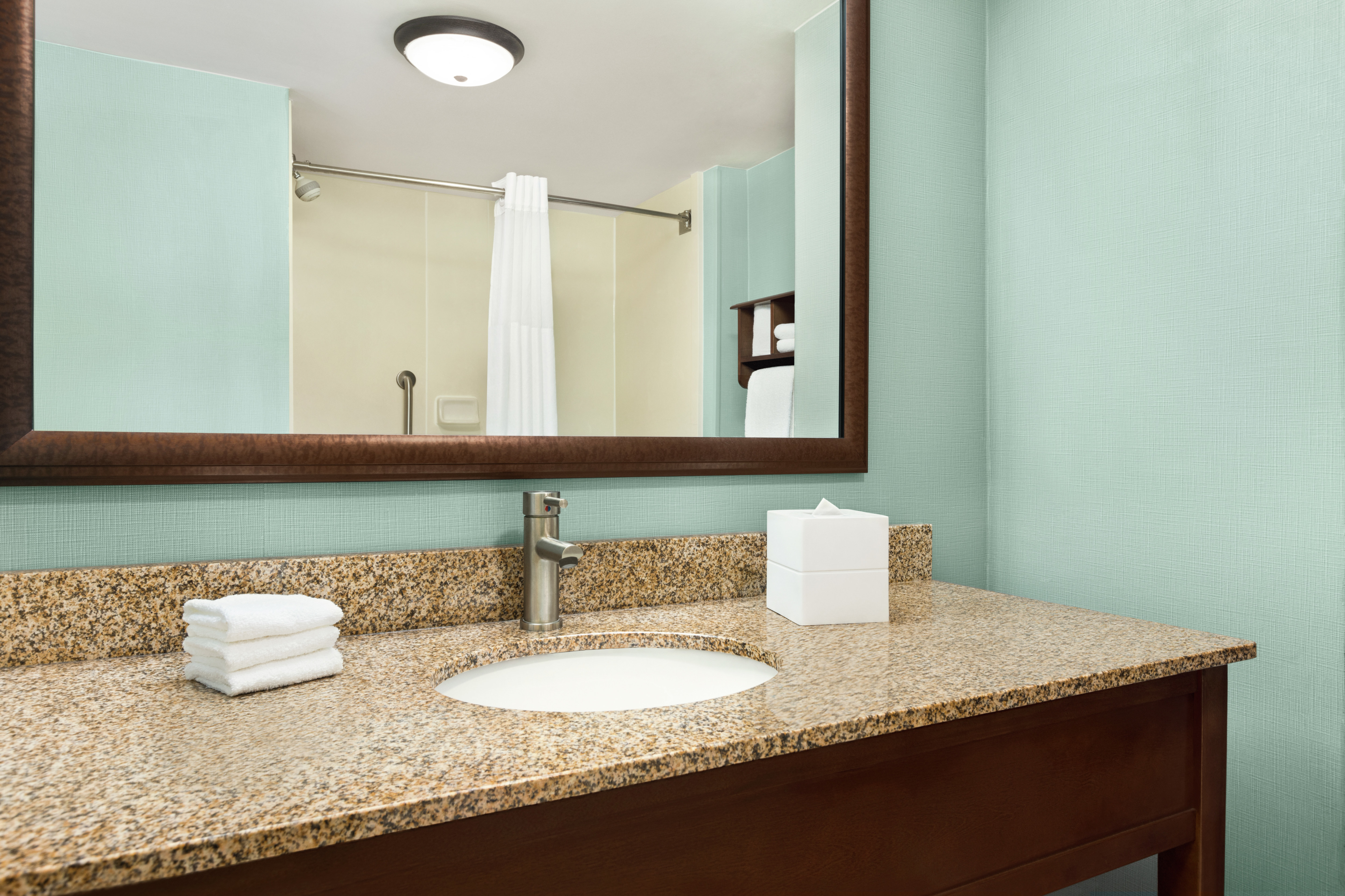 Spacious guest bathroom featuring large vanity, mirror, and tub with shower.