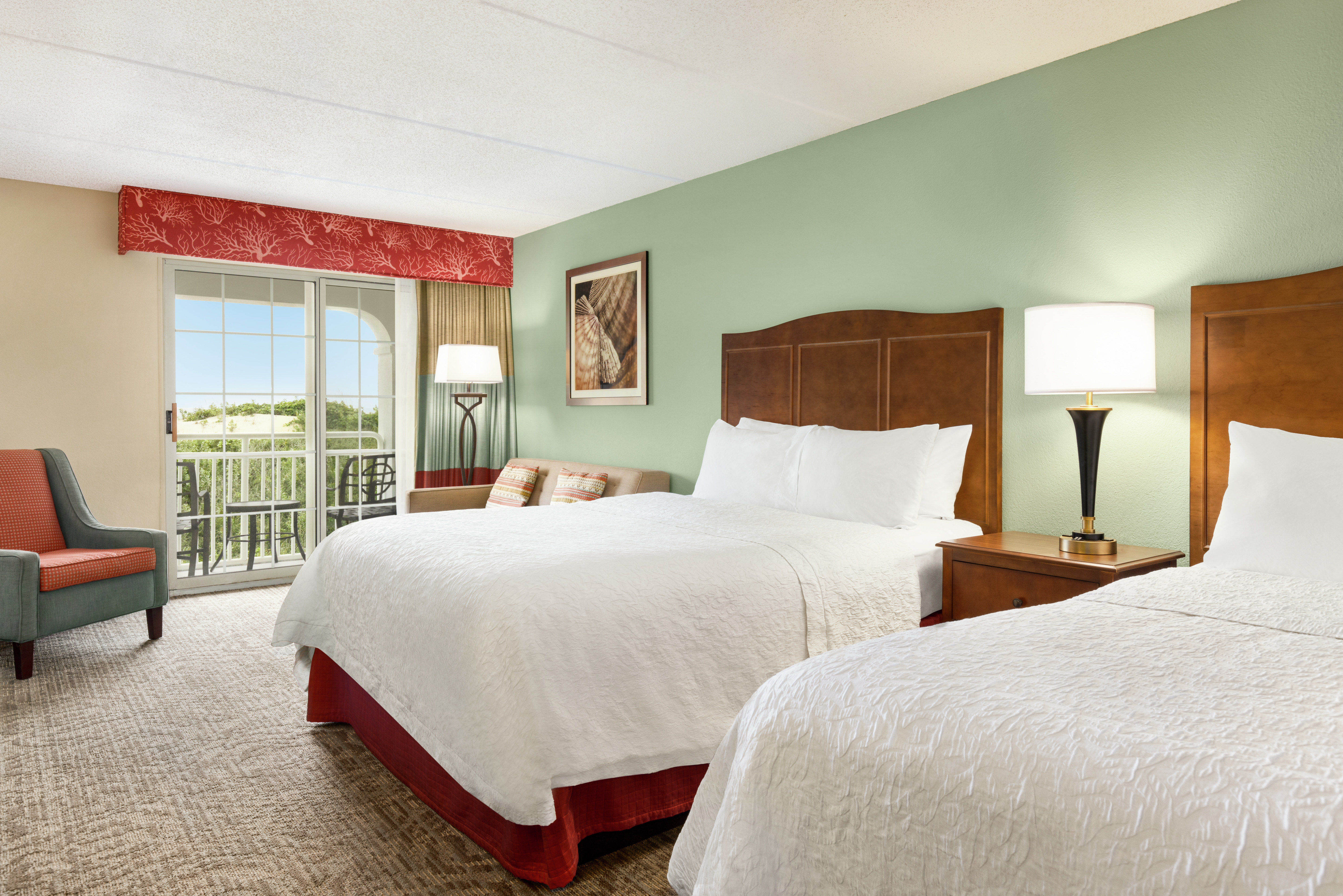 Spacious guestroom featuring two comfortable queen beds and ocean view.