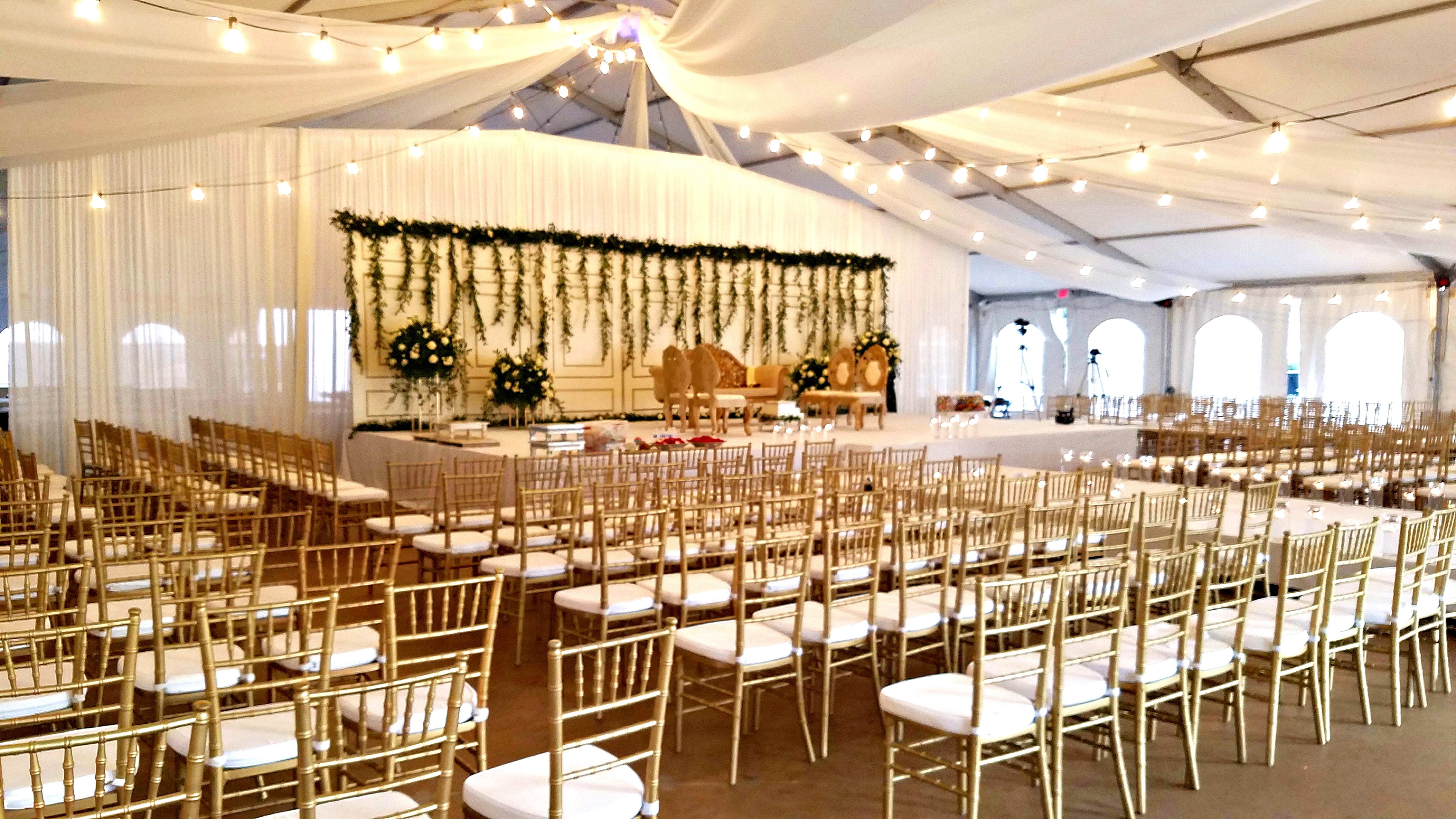 Wedding Reception Tent Setup with Rows of Chairs and Stage Area