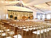 Wedding Reception Tent Setup with Rows of Chairs and Stage Area