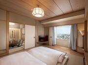 Bedroom in Tatami Styled Family Suite With Bed, TV, Window With Open Drapes to City View, and Open Doorway to Dining Area