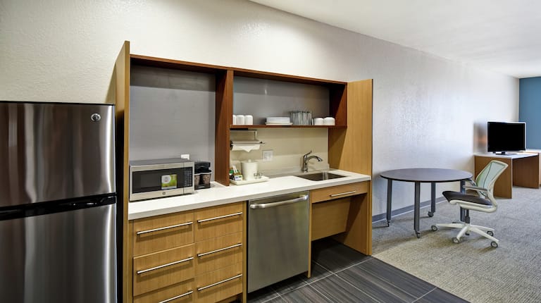 客房厨房区域,配有水槽、微波炉、冰箱和休息区。