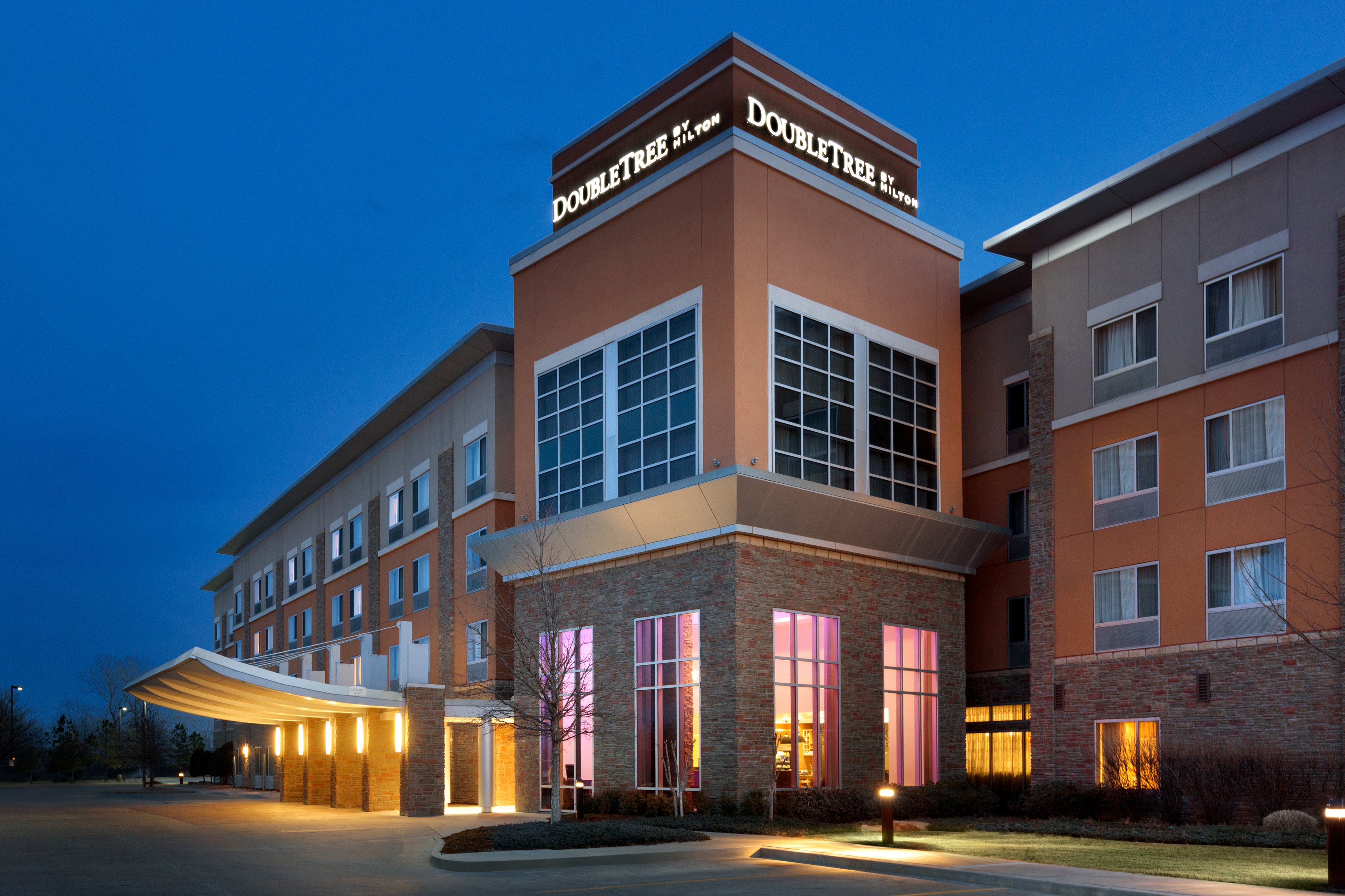 Illuminated Hotel Exterior, Signage, Porte Cochere, Landscaping, and Parking Lot at Dusk