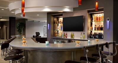 Counter Seating and TV at Fully Stocked Bar With Lounge Seating in Background
